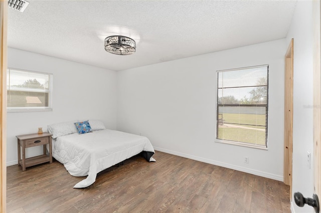 bedroom with multiple windows, wood finished floors, and visible vents