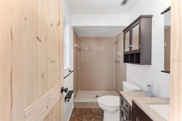 full bathroom with vanity, toilet, visible vents, and a tile shower