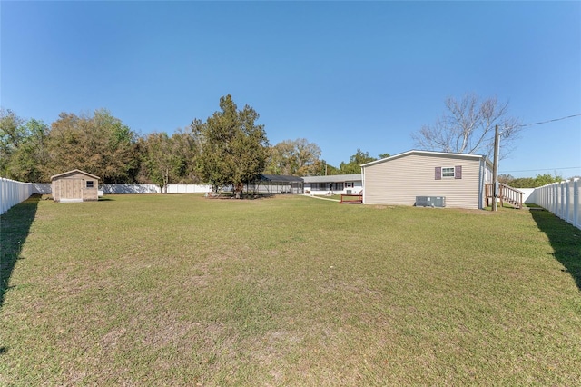 view of yard with an outdoor structure, central AC unit, a fenced backyard, and a shed