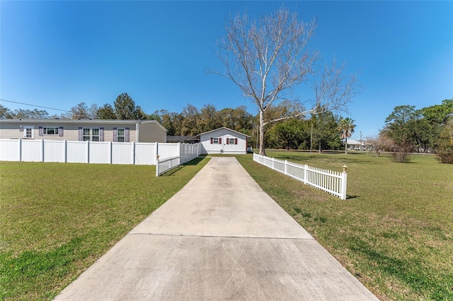 view of front of property with concrete driveway, a front yard, and fence