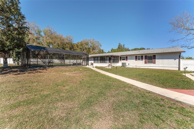 view of front of home featuring glass enclosure, a front yard, and fence