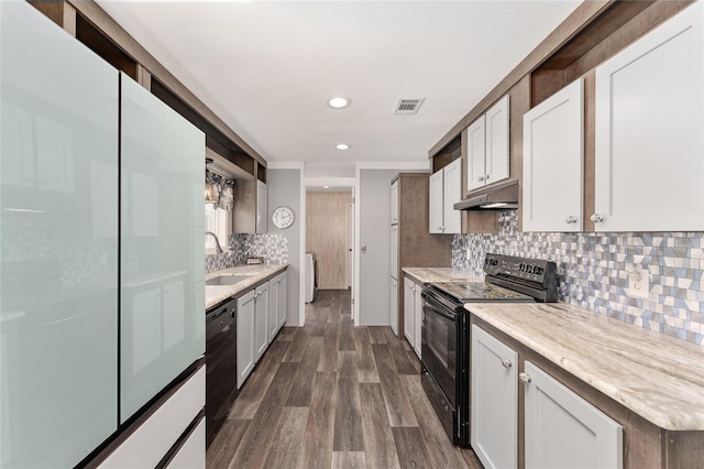 kitchen with visible vents, a sink, under cabinet range hood, black appliances, and dark wood-style flooring