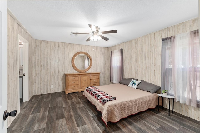 bedroom with dark wood-type flooring, a ceiling fan, and a textured ceiling