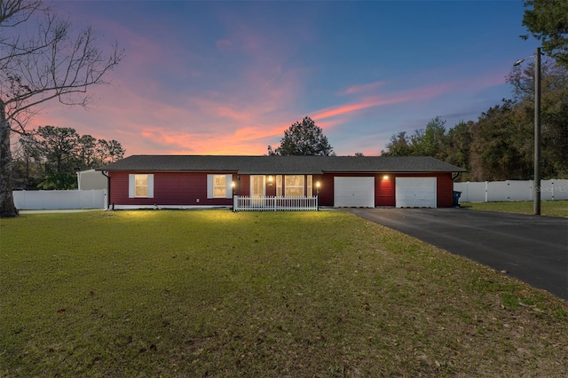 ranch-style house featuring a front yard, an attached garage, driveway, and fence