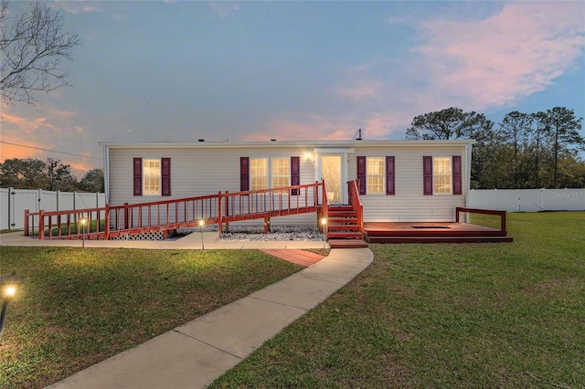 manufactured / mobile home with a wooden deck, a fenced backyard, and a front lawn