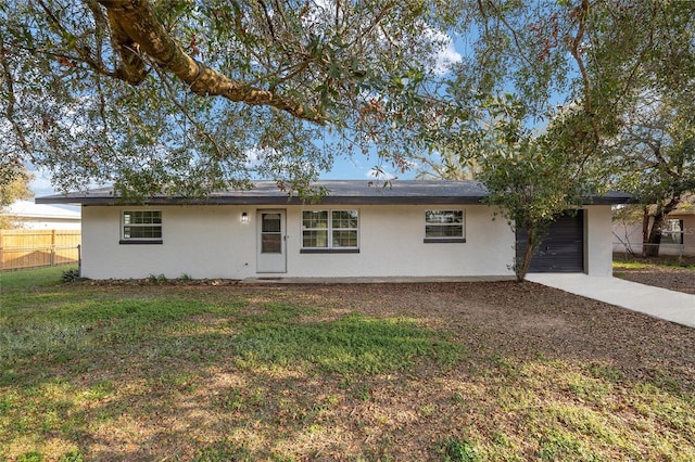 ranch-style home featuring a garage, concrete driveway, fence, a front yard, and stucco siding