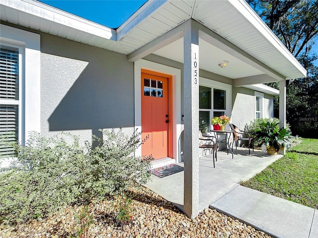 doorway to property featuring a porch and stucco siding