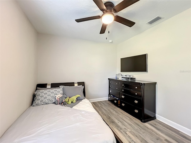 bedroom featuring baseboards, visible vents, ceiling fan, and wood finished floors