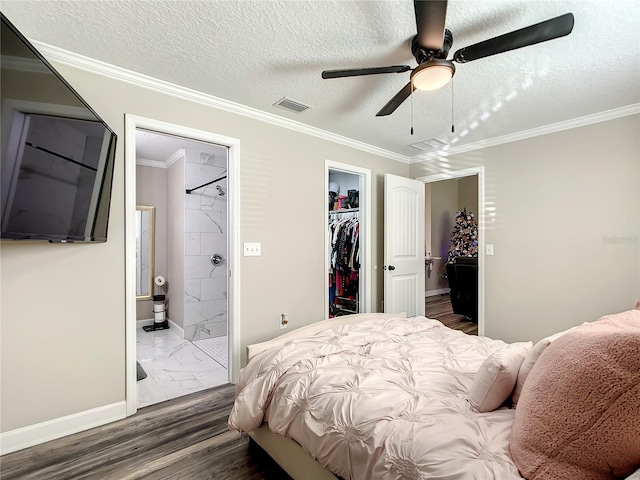 bedroom with ensuite bathroom, visible vents, a closet, a walk in closet, and crown molding