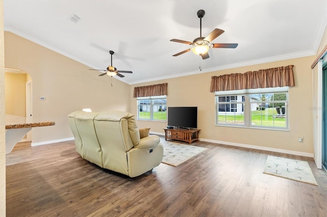 living area with arched walkways, wood finished floors, visible vents, baseboards, and crown molding