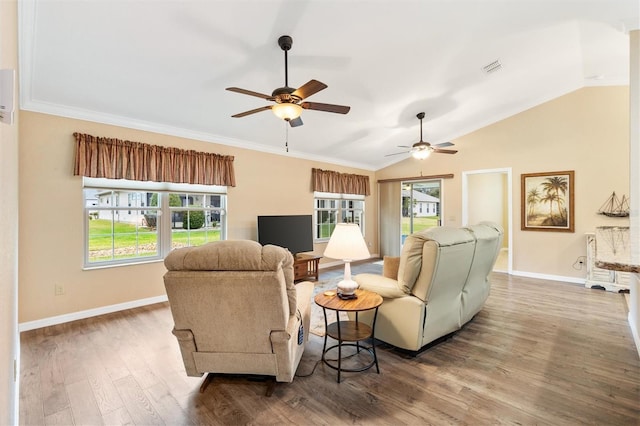 living area with baseboards, vaulted ceiling, a wealth of natural light, and wood finished floors