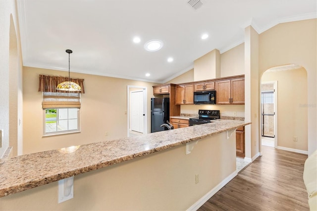 kitchen with black appliances, ornamental molding, a breakfast bar area, and visible vents