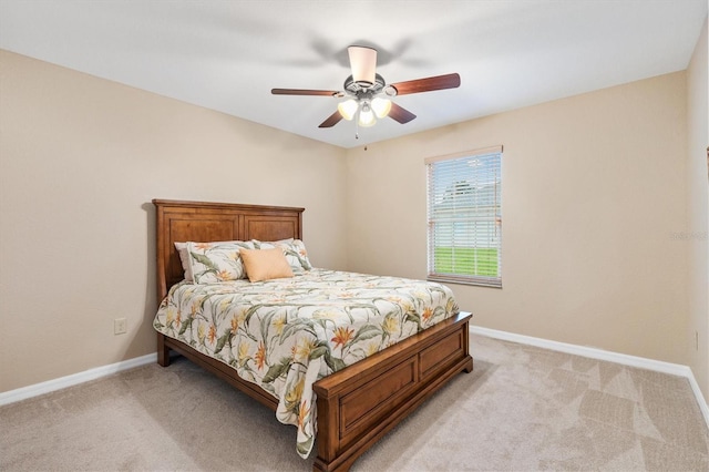 bedroom with light colored carpet, ceiling fan, and baseboards