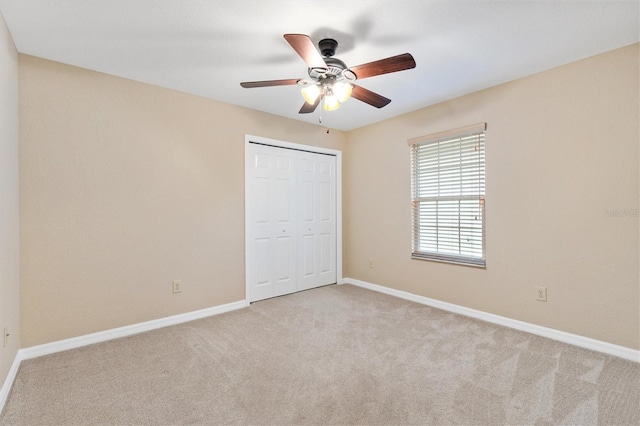 unfurnished bedroom featuring a closet, light carpet, ceiling fan, and baseboards