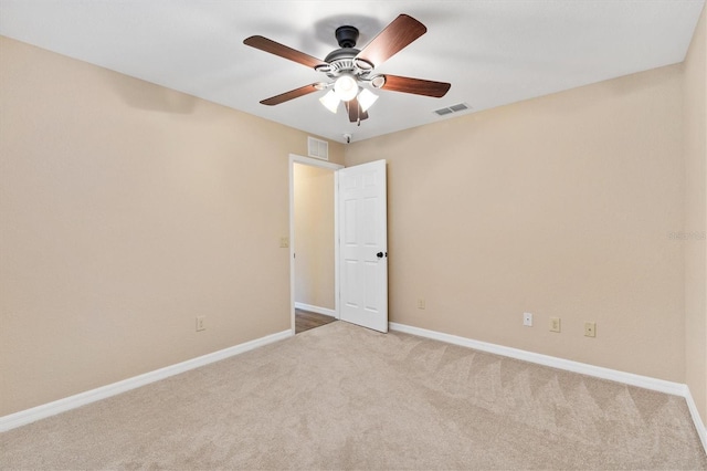 carpeted spare room featuring visible vents, ceiling fan, and baseboards