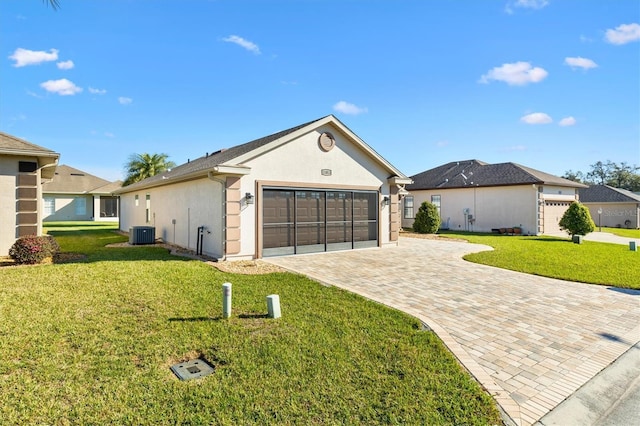 view of front facade with a front yard, central AC unit, decorative driveway, and stucco siding