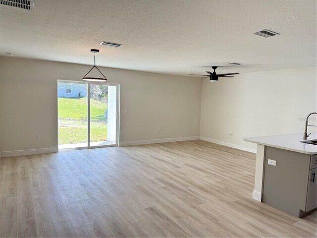31 Juniper Pass Ln, Ocala, FL 34480 - unfurnished living room featuring light wood-style floors, baseboards, a sink, ceiling fan, and a textured ceiling