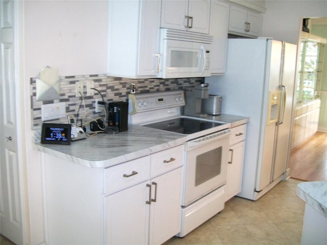 kitchen with tasteful backsplash, white appliances, and white cabinetry