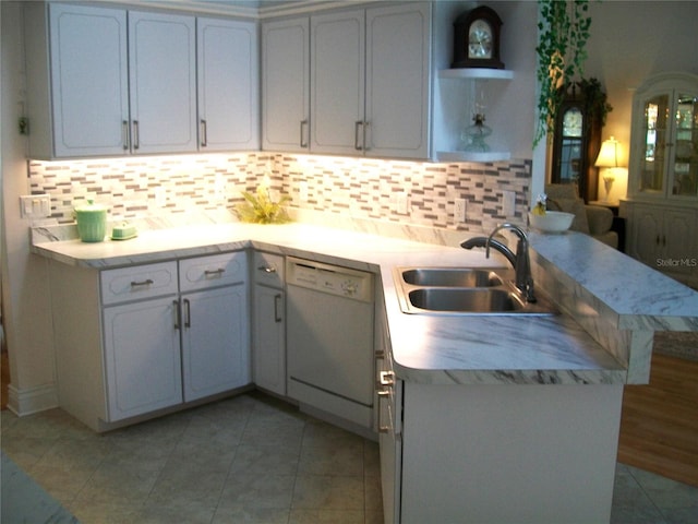 kitchen featuring dishwasher, a peninsula, light countertops, open shelves, and a sink