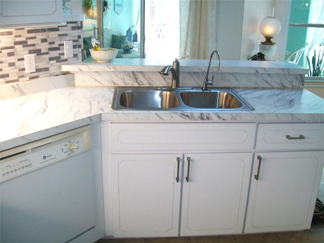 kitchen featuring decorative backsplash, white cabinetry, white dishwasher, and a sink