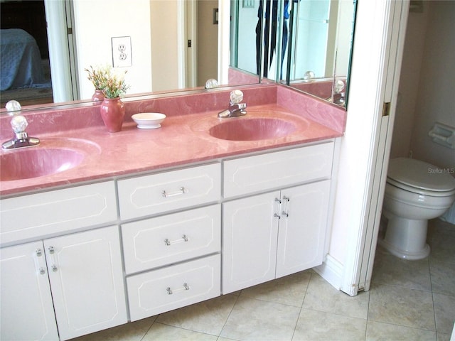 full bath featuring double vanity, tile patterned flooring, a sink, and toilet