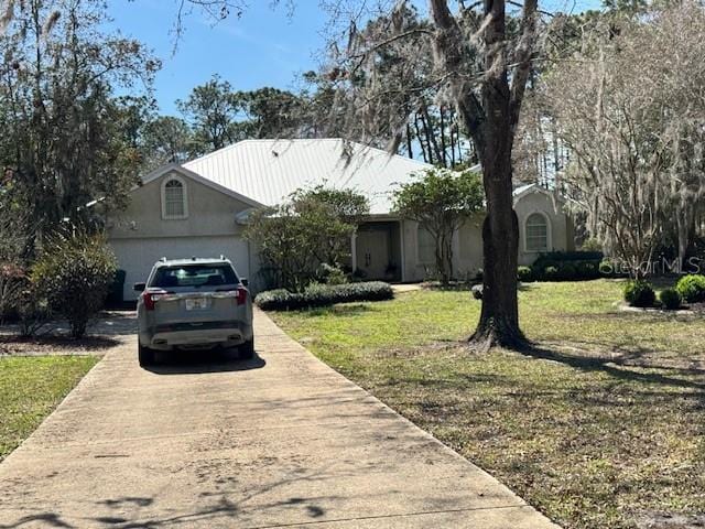 view of front facade featuring concrete driveway, an attached garage, a front lawn, and stucco siding