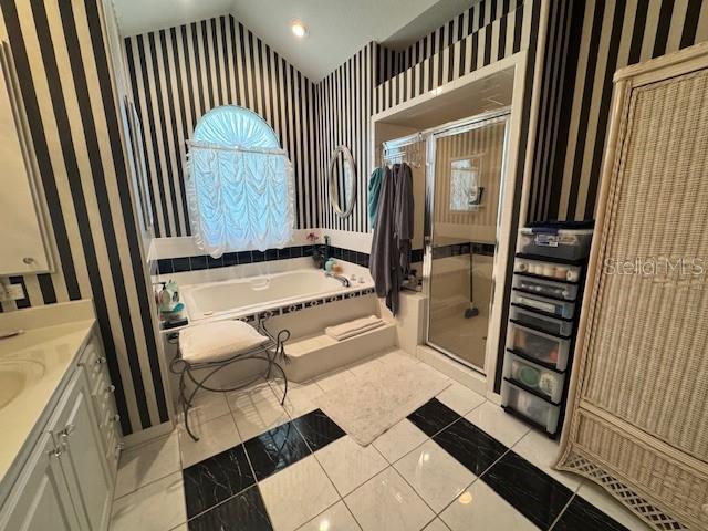 bathroom featuring vanity, wallpapered walls, a shower stall, vaulted ceiling, and a garden tub