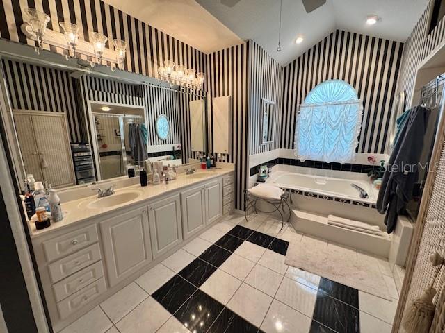 full bath featuring a sink, a bath, double vanity, and wallpapered walls