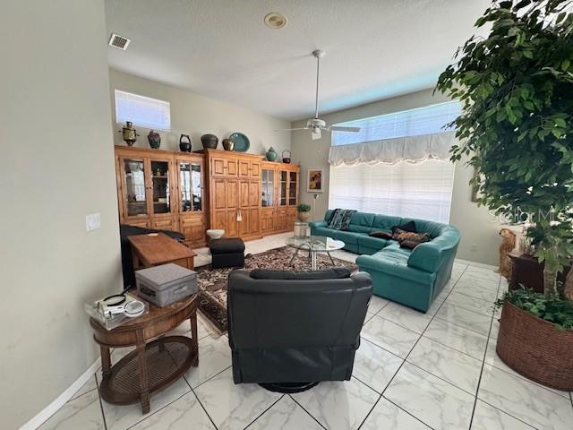 living room with baseboards, visible vents, plenty of natural light, and marble finish floor