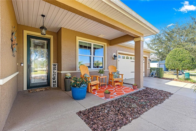 entrance to property featuring a garage, concrete driveway, a porch, and stucco siding