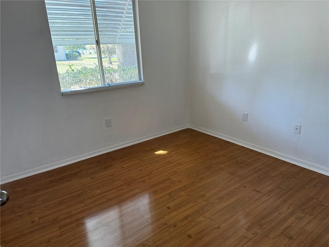 unfurnished room with dark wood-type flooring and baseboards