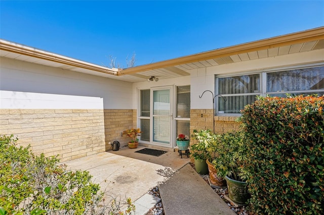 property entrance with brick siding and a patio