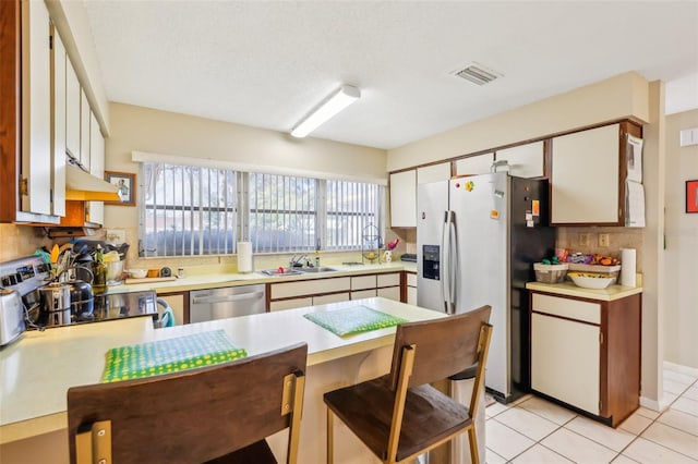 kitchen featuring stainless steel appliances, visible vents, light countertops, a sink, and a peninsula