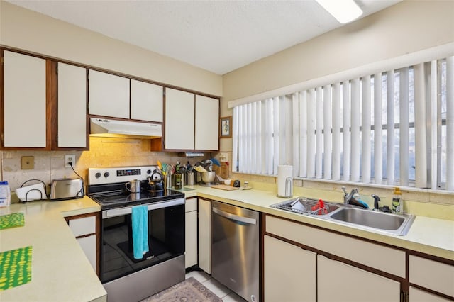 kitchen featuring stainless steel appliances, light countertops, under cabinet range hood, white cabinetry, and a sink