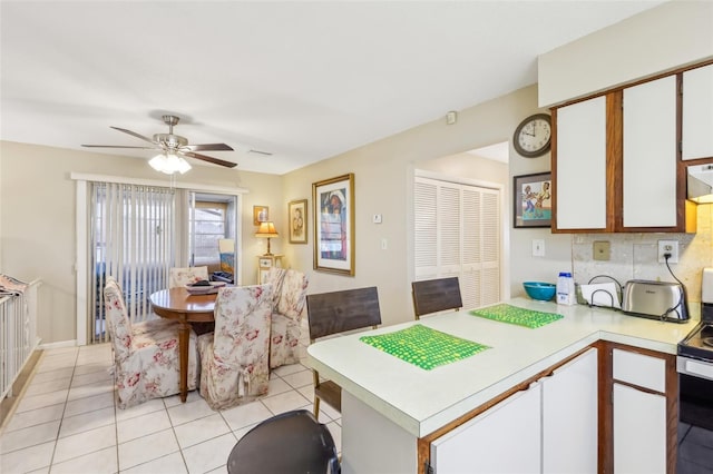 kitchen featuring light tile patterned floors, white cabinets, electric stove, a peninsula, and light countertops