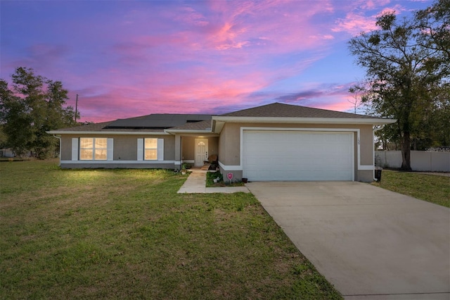 ranch-style home with an attached garage, concrete driveway, roof mounted solar panels, a front lawn, and stucco siding