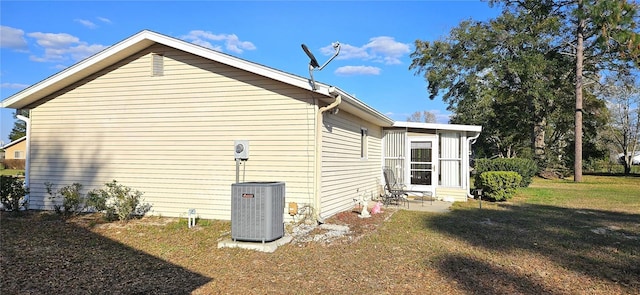 view of side of property featuring central air condition unit, entry steps, and a yard