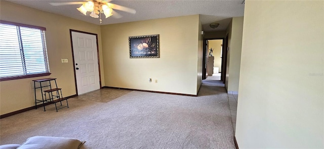 carpeted spare room featuring ceiling fan, baseboards, and a textured ceiling