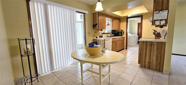 kitchen featuring light tile patterned floors, washing machine and dryer, light countertops, brown cabinets, and dishwasher