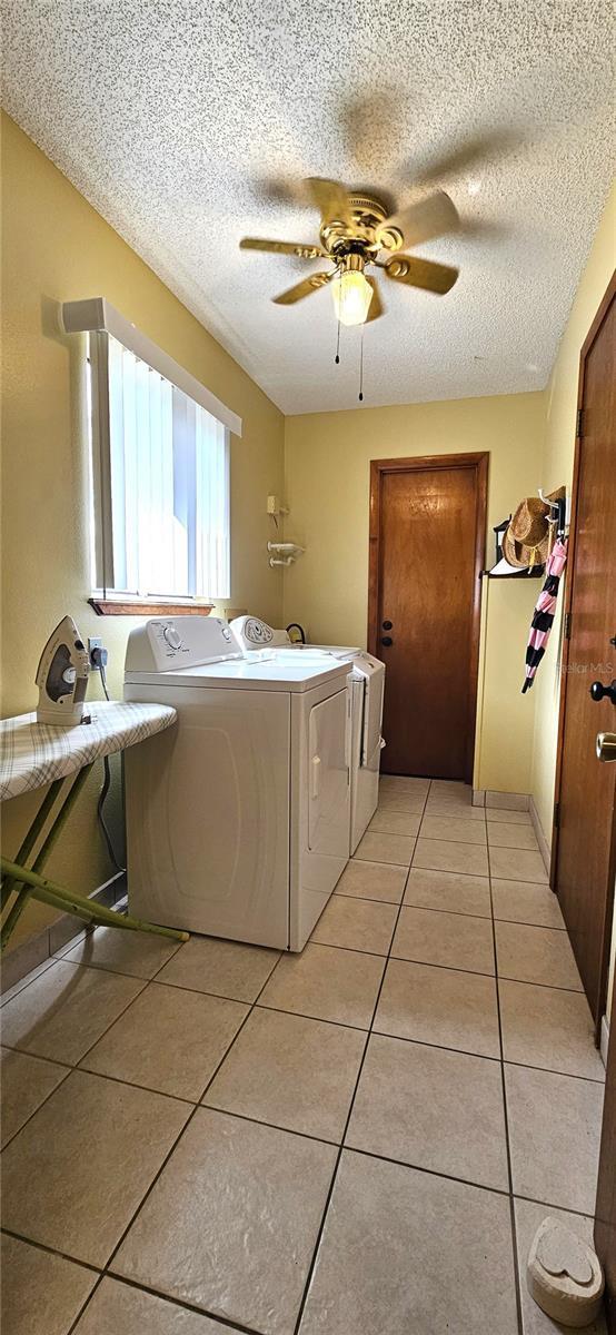 laundry room with laundry area, light tile patterned floors, a ceiling fan, independent washer and dryer, and a textured ceiling