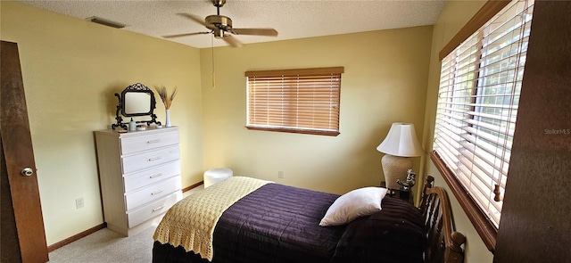 bedroom featuring baseboards, light colored carpet, visible vents, and a textured ceiling