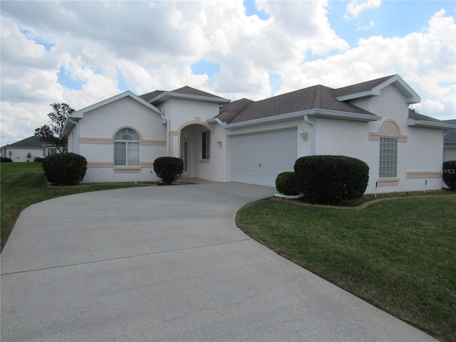 single story home with a garage, driveway, a front lawn, and stucco siding