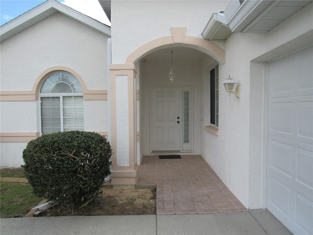 view of exterior entry featuring a garage and stucco siding