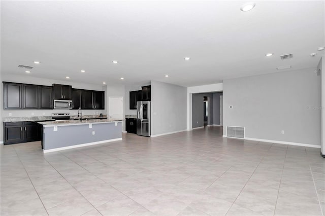 kitchen with open floor plan, stainless steel appliances, light countertops, and visible vents