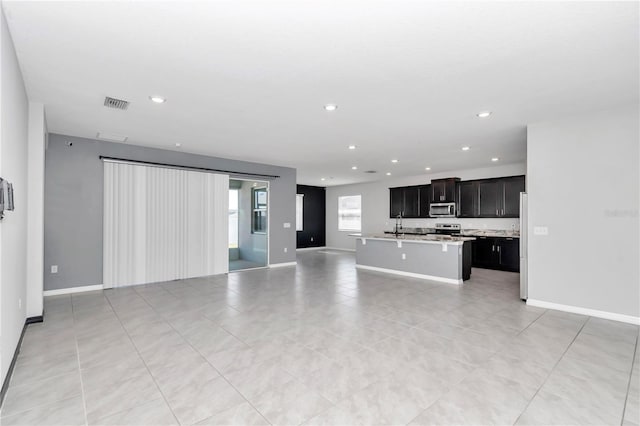 unfurnished living room featuring baseboards, visible vents, and recessed lighting