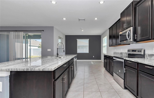 kitchen with a kitchen island with sink, a sink, visible vents, appliances with stainless steel finishes, and light stone countertops