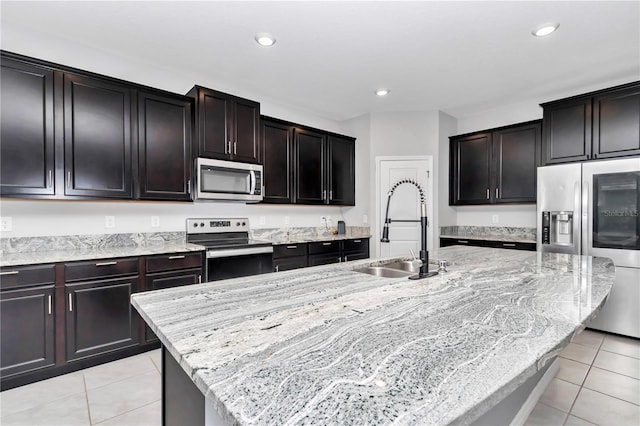 kitchen featuring stainless steel appliances, a sink, a center island with sink, and light tile patterned floors