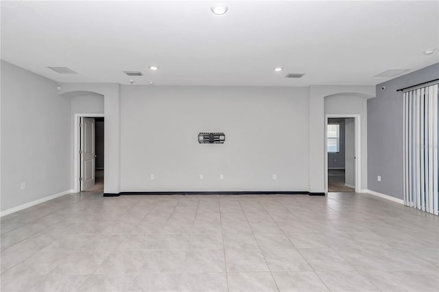 unfurnished room featuring arched walkways, visible vents, and recessed lighting