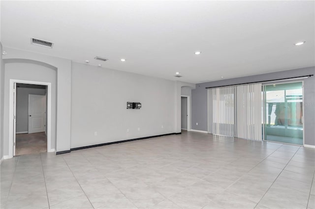 unfurnished room with baseboards, visible vents, arched walkways, and recessed lighting