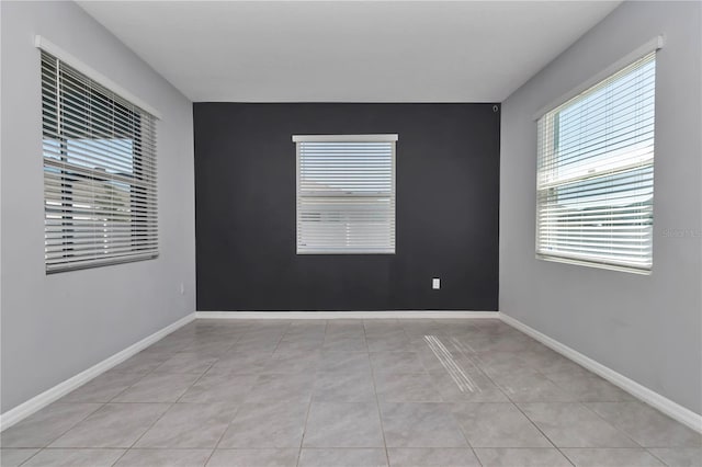 empty room featuring light tile patterned floors and baseboards